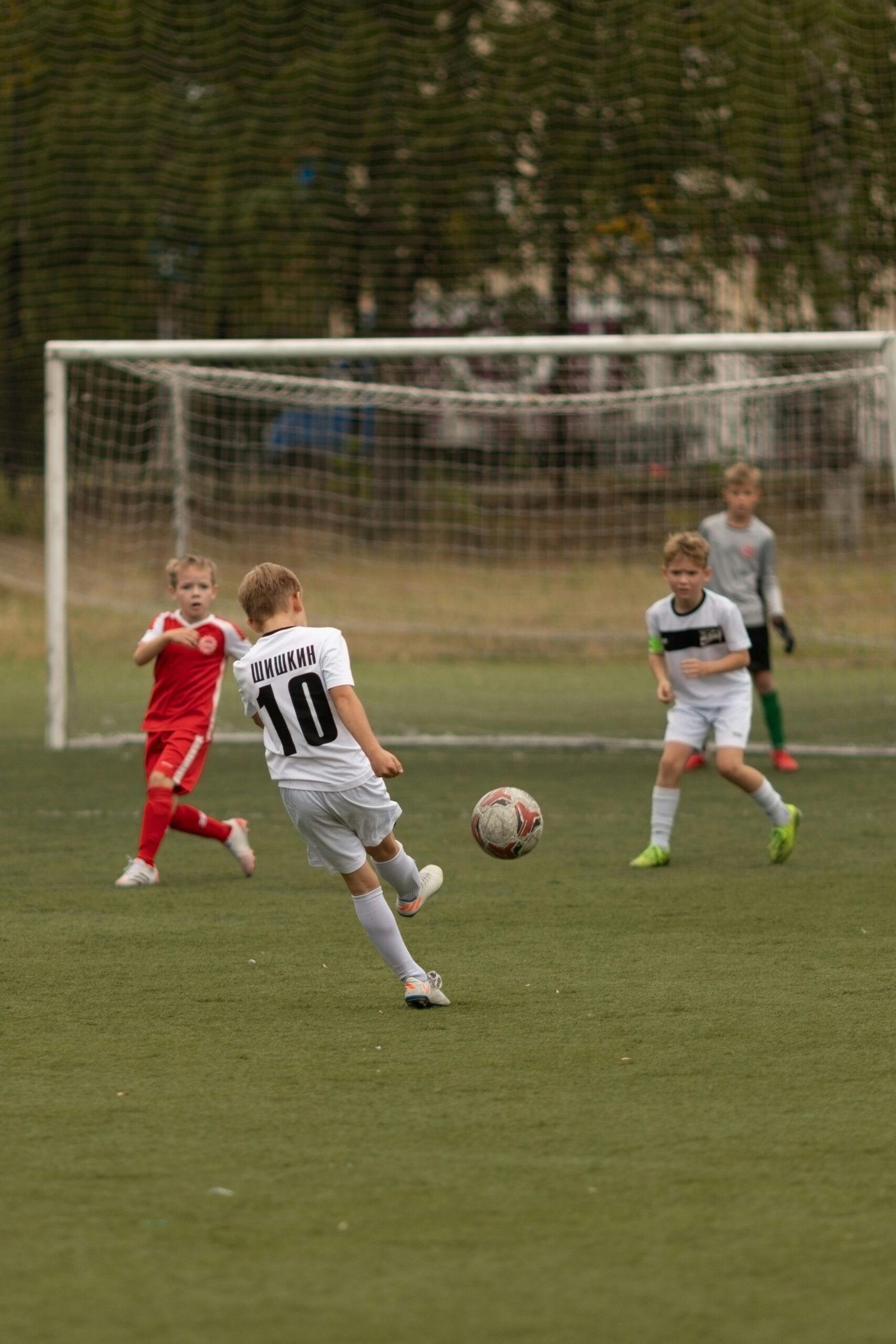 Young boys playing soccer on an outdoor field during the day. Action shot with goalpost.