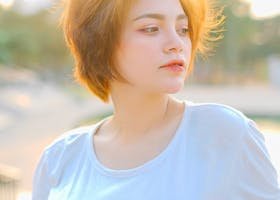 A young woman enjoying a summer day outdoors, dressed in casual attire with a thoughtful expression.